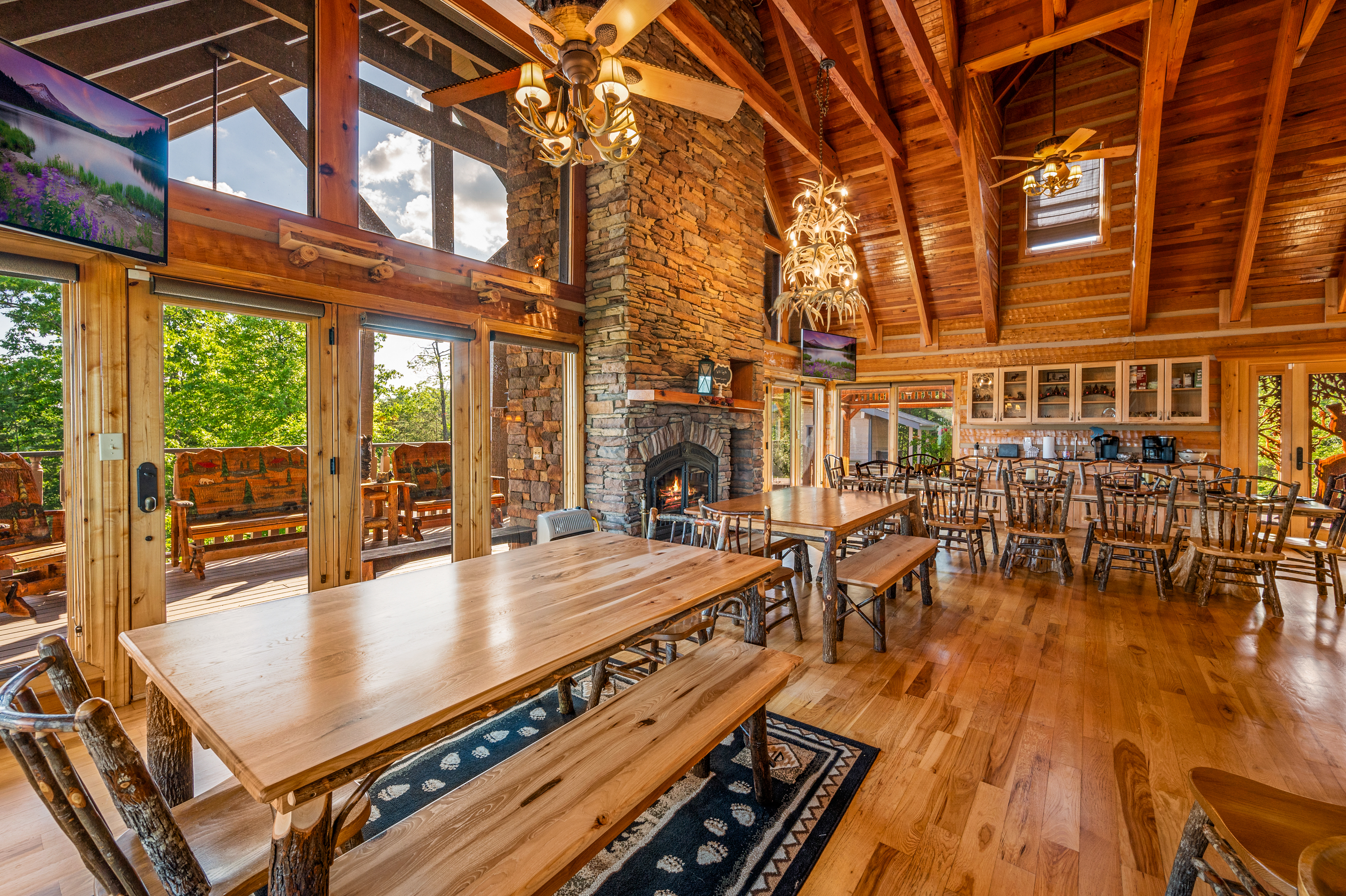 Large dining room with multiple tables beneath timber rafters and a stone fireplace